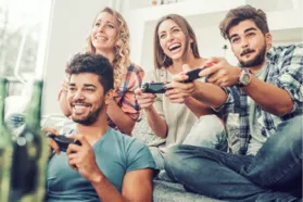 A group of four friends laughing while using game controllers