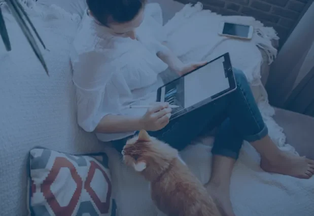 Woman drawing on a tablet with a cat nearby