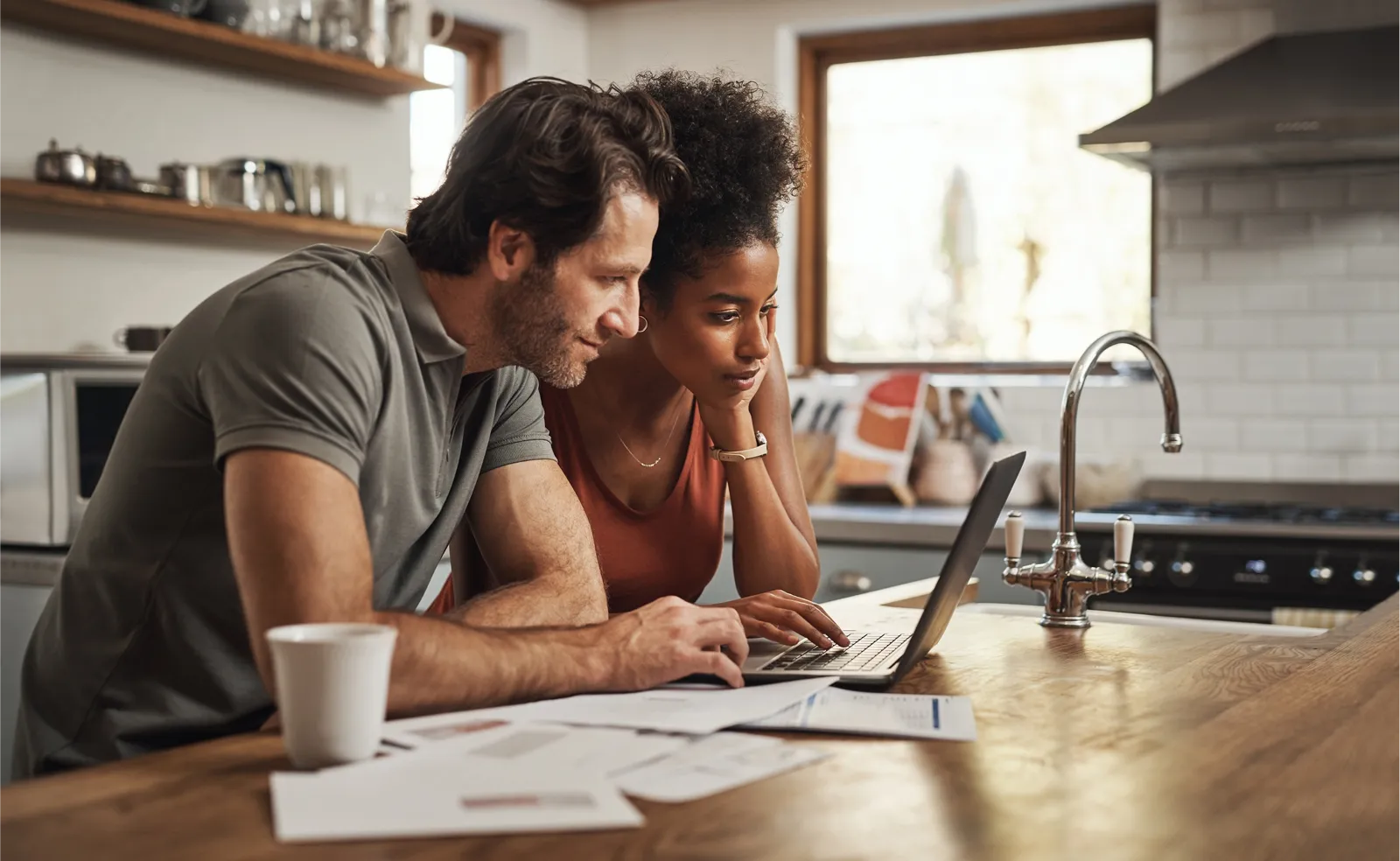 Couple using a laptop at the kitchen counter