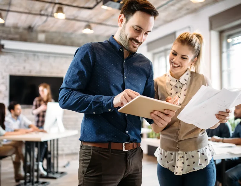 Employees standing in an office discussing something over a tablet