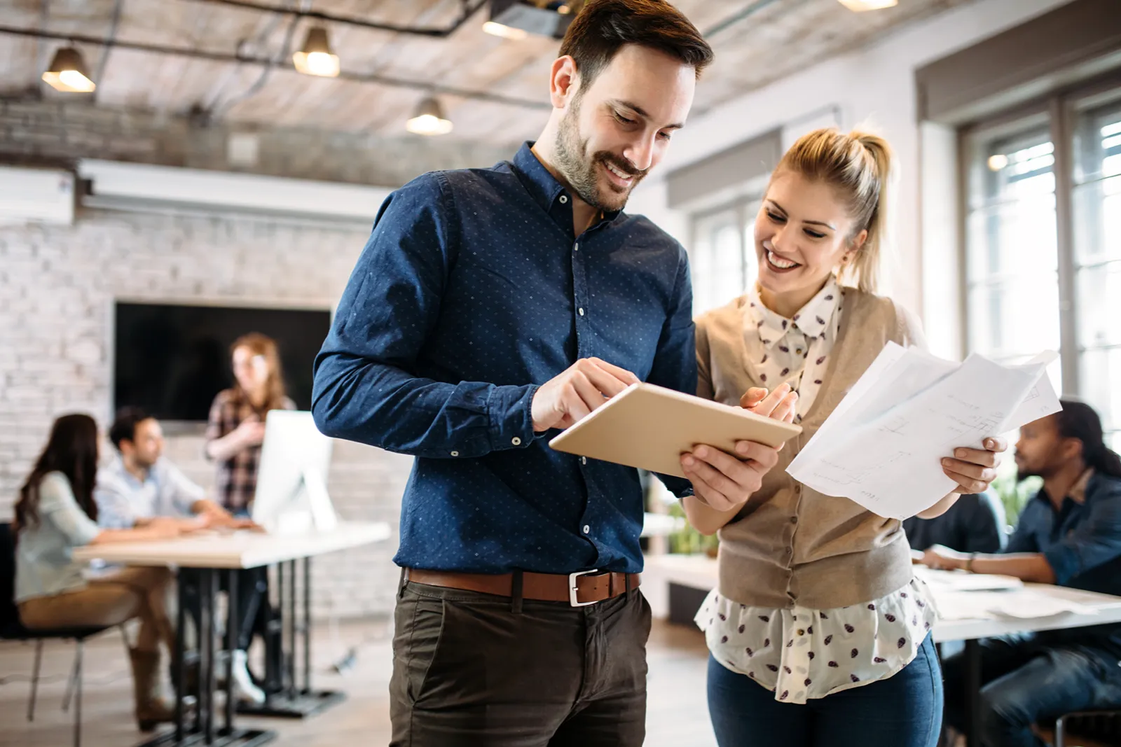 Employees standing in an office discussing something over a tablet