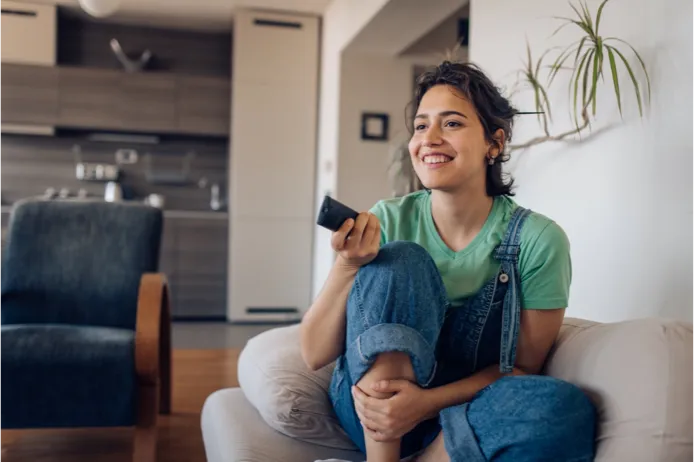 Woman watching TV on the couch with a remote