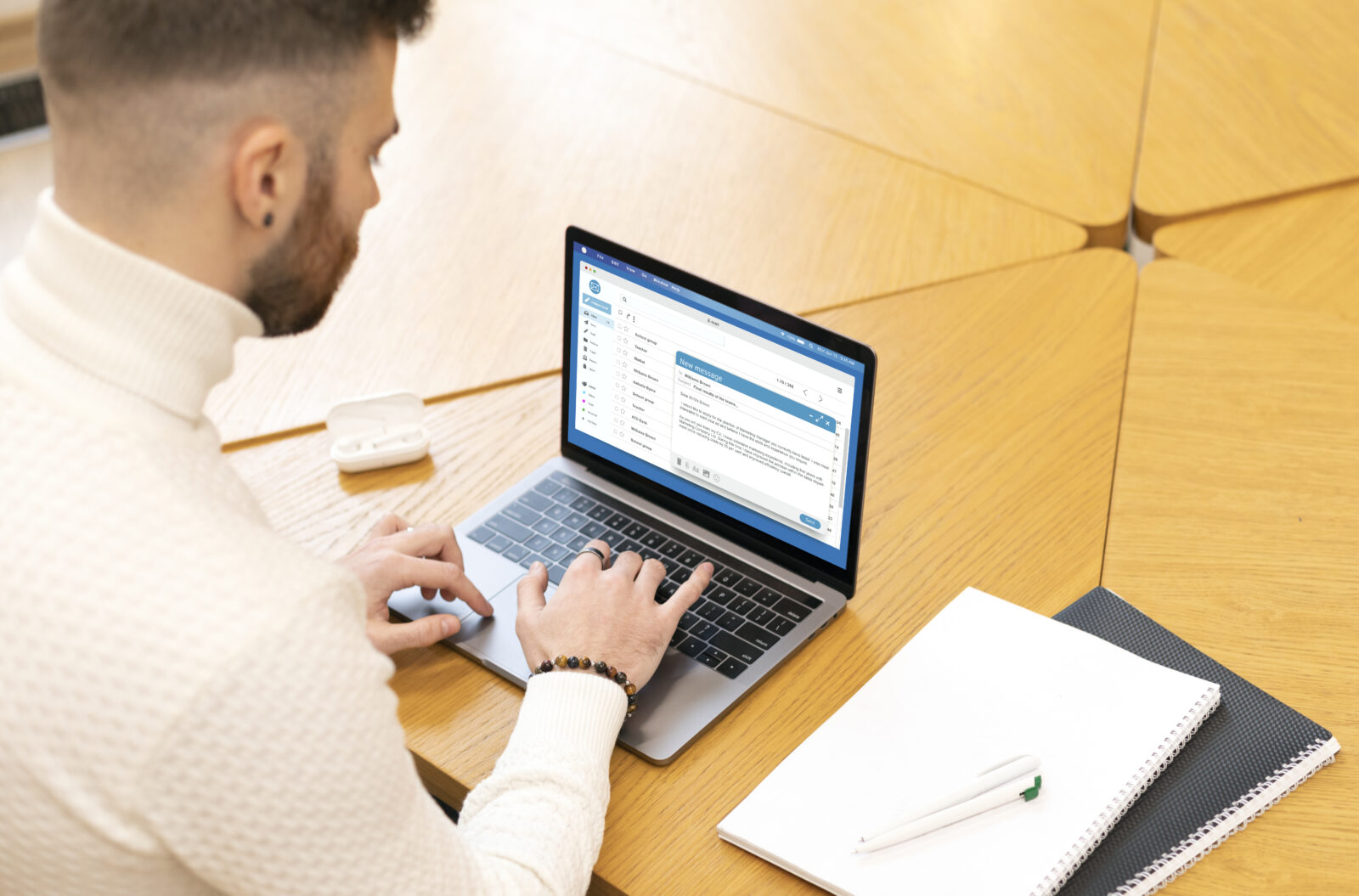 A young man in a white sweater typing on a laptop in a bright, modern study environment, reflecting a focused approach to completing tasks related to the 