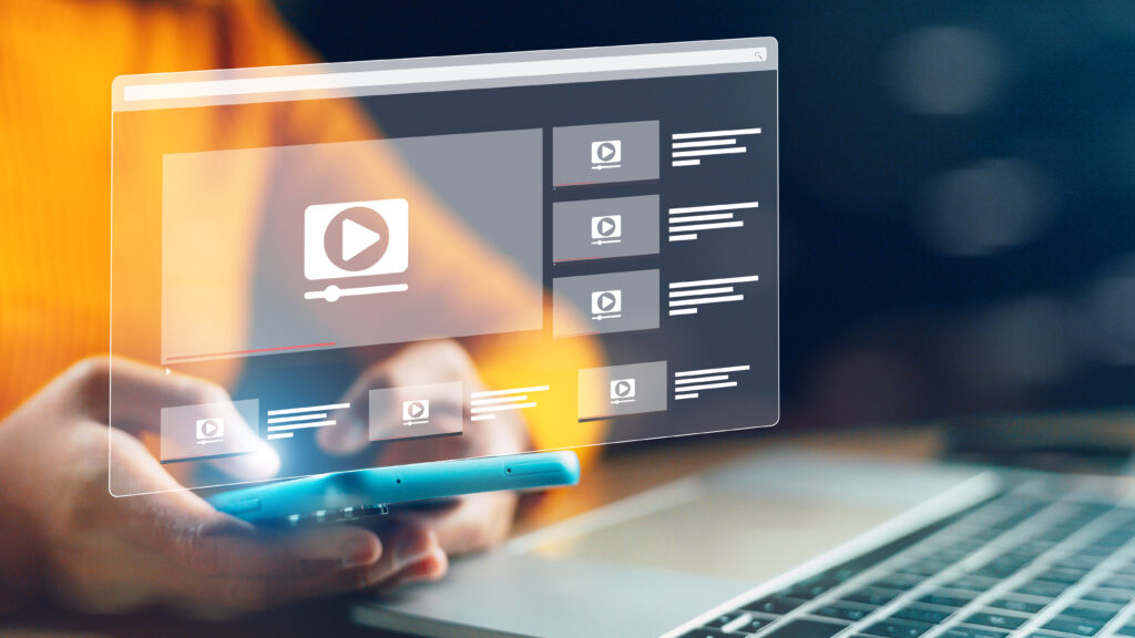 a close-up of a person using a smartphone to navigate through a video streaming platform. The layered interface with video thumbnails suggests a search for specific content, potentially to execute a "cancel directv" related to media or entertainment consumption.