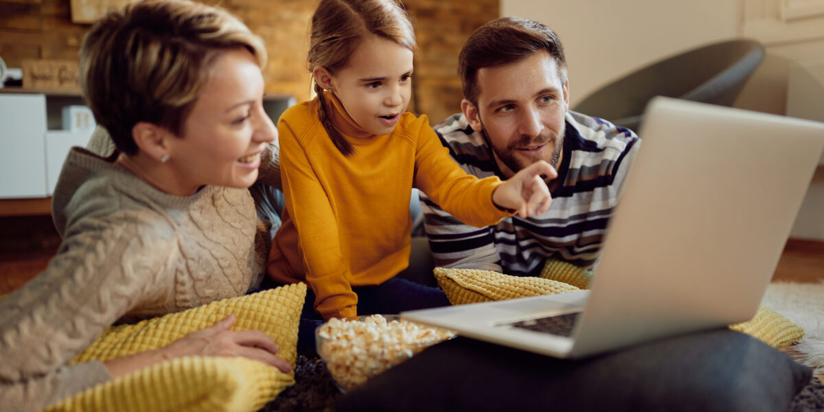 A family of three relaxes at home, watching a laptop together. This image highlights how the best cable internet deals can bring families together for streaming, browsing, and entertainment.